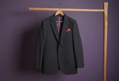 A tailored suit jacket hanging on a wooden hanger
