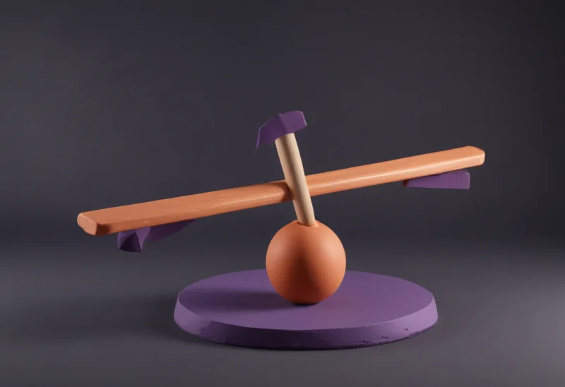 A wooden see-saw plank balanced on a round fulcrum, one end dipped low and the other raised