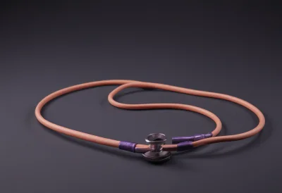 A coiled stethoscope resting on a smooth tabletop, its chest-piece lying flat