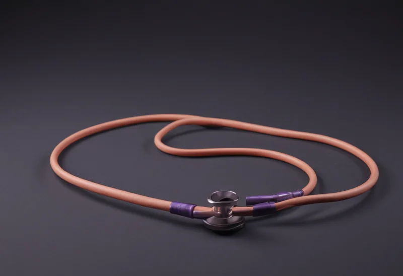 A coiled stethoscope resting on a smooth tabletop, its chest-piece lying flat