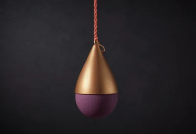 A polished brass plumb bob hanging motionless and vertical from a single thread