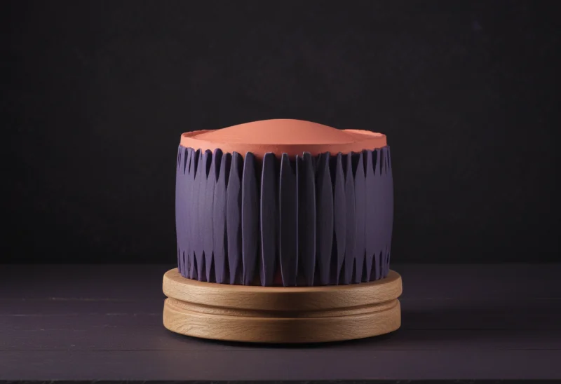 A slotted zoetrope drum on a small wooden base, caught mid-spin.