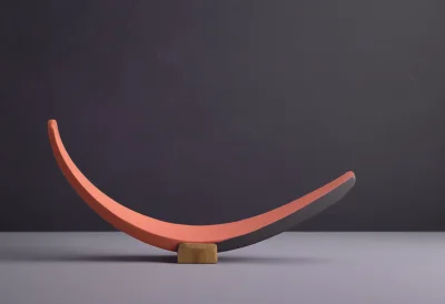 A curved wooden boomerang resting on a flat surface