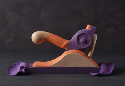 A wooden hand plane peeling a single curled shaving from a board