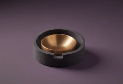 A polished brass calibration weight resting in a felt-lined case slot